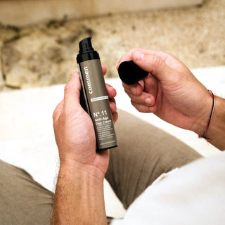 Commen Nº.11 Anti-Age Day Cream in a man's hands: the bottle in one hand, the cap in the other.