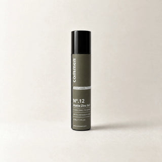 Commen Nº.12 Matte Zinc Gel, a slim 50 ml airless pump bottle with an olive label, standing on light paper.