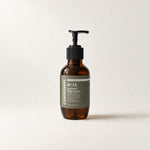 Commen Nº.15 Patchouli Body Serum, a 270 ml amber pump bottle with an olive label, standing on light paper.