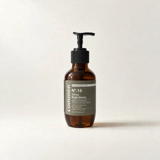 Commen Nº.16 Citrus Body Serum, a 270 ml amber pump bottle with an olive label, standing on light paper.