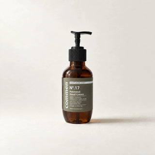 Commen Nº.17 Patchouli Hand Cream, een amberkleurige pompfles van 270 ml met olijfgroen etiket, staand op licht papier.
