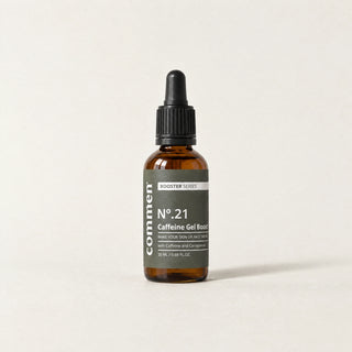 Commen Nº.21 Caffeine Gel Boost, an amber dropper bottle with a dark label, standing on light paper.