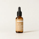 Commen Nº.32 Smooth Beard Oil, een amberkleurige pipetfles met lichtbruin etiket, staand op licht papier.