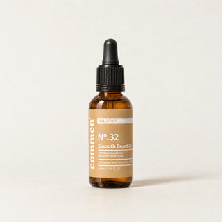 Commen Nº.32 Smooth Beard Oil, een amberkleurige pipetfles met lichtbruin etiket, staand op licht papier.